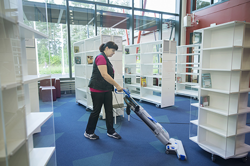 Laitoshuoltaja siivoaa Nepenmäen kirjastoa.